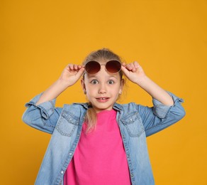 Photo of Emotional girl wearing stylish sunglasses on orange background