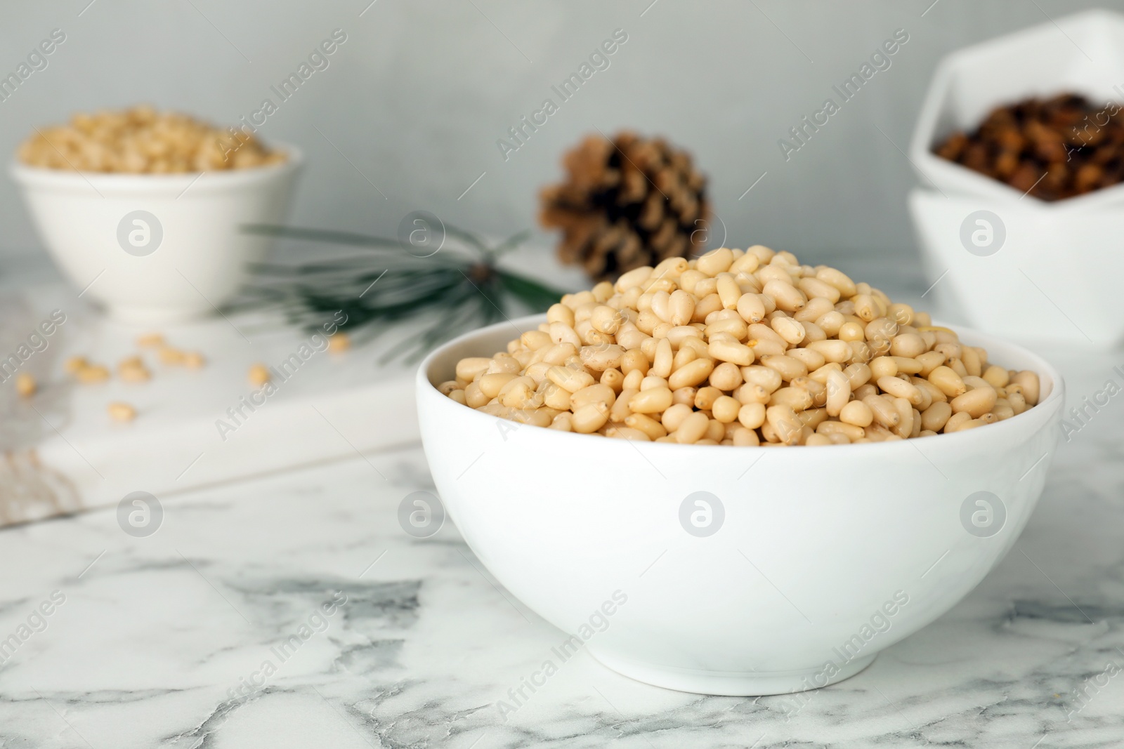 Photo of Bowl with pine nuts on marble table. Space for text