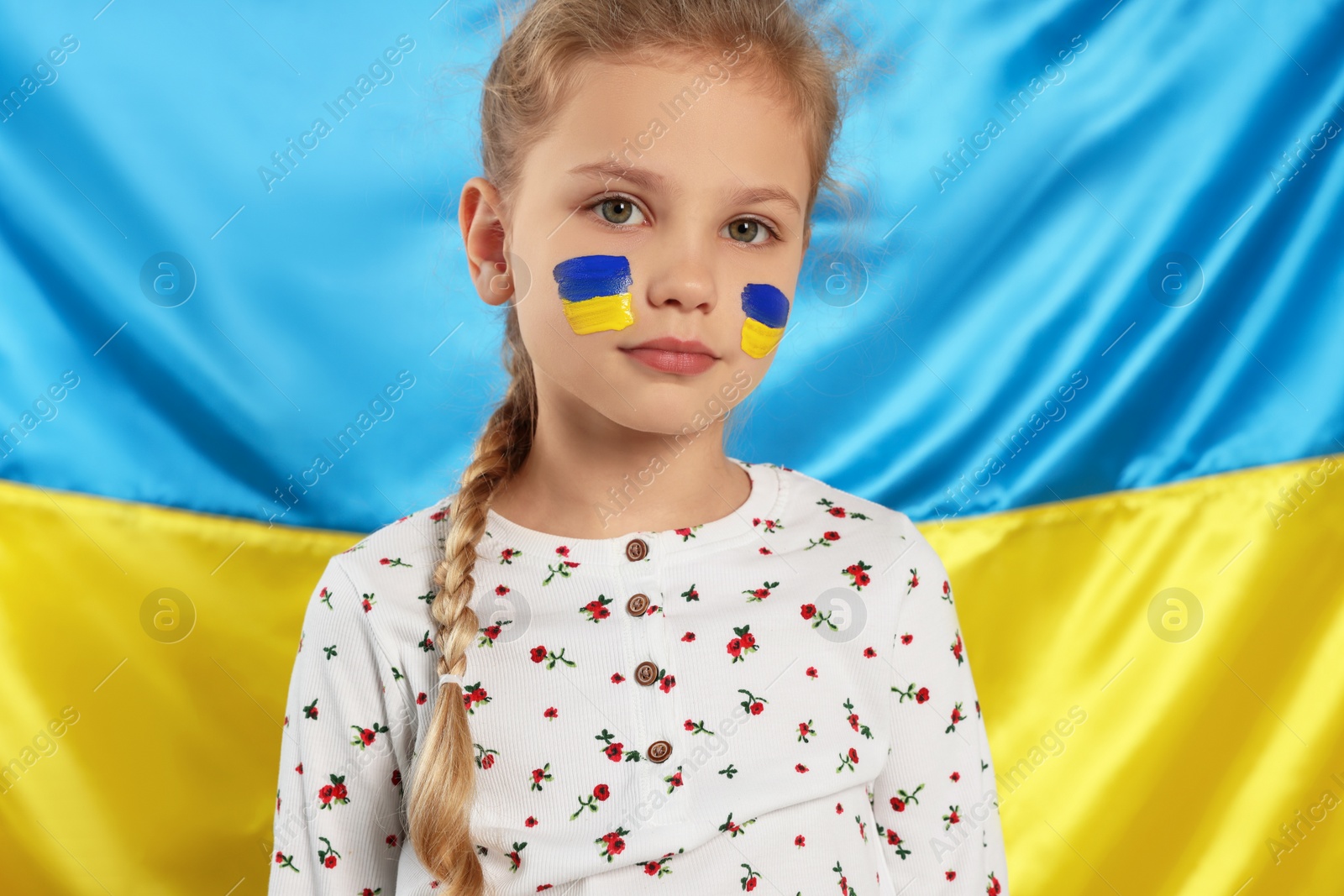 Photo of Little girl with face paint near Ukrainian flag