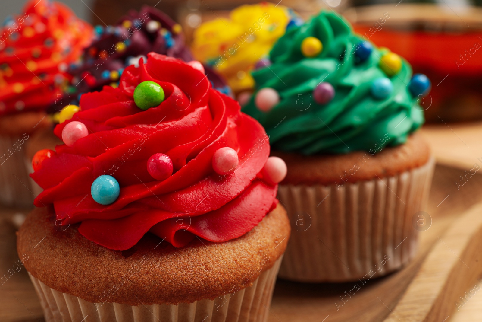 Photo of Delicious cupcakes with colorful cream and sprinkles, closeup