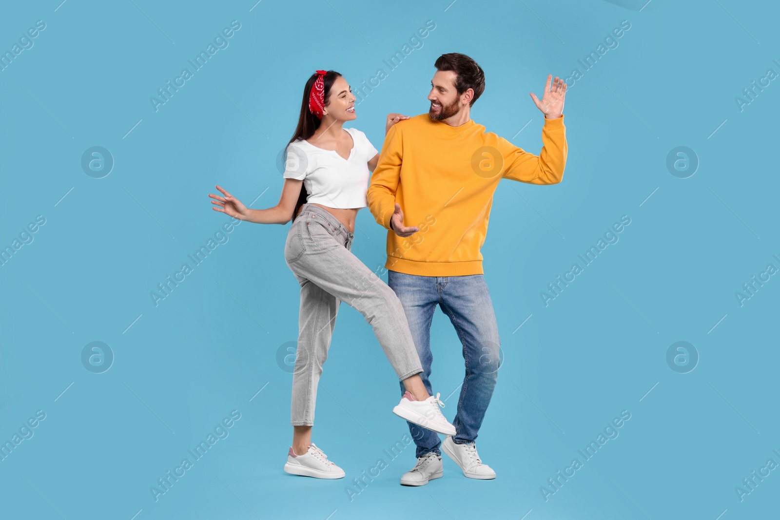 Photo of Happy couple dancing together on light blue background