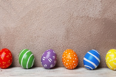 Decorated Easter eggs on table near color wall. Space for text