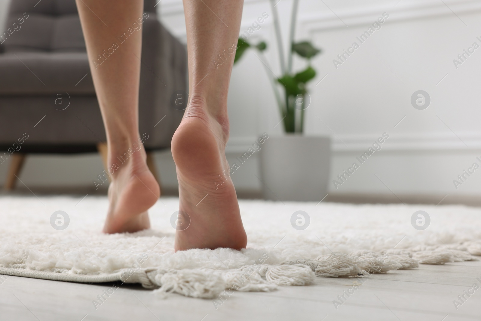 Photo of Woman walking on soft white carpet at home, closeup. Space for text