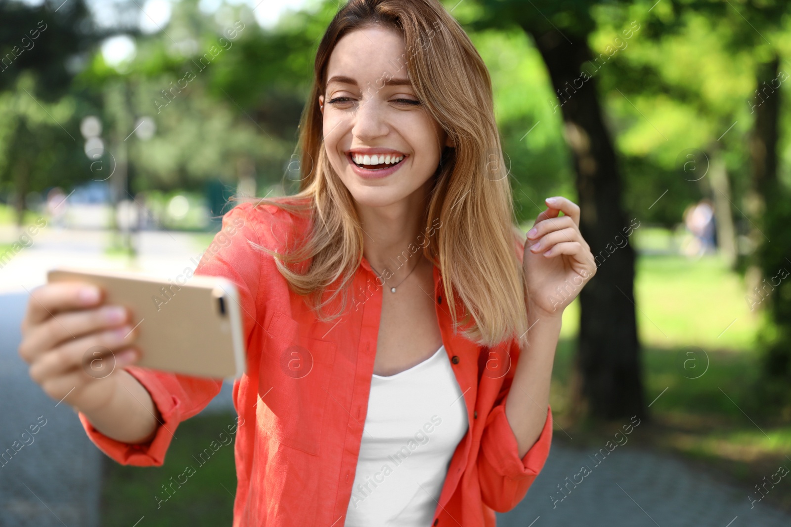 Photo of Happy young woman taking selfie in park