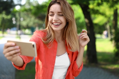 Photo of Happy young woman taking selfie in park