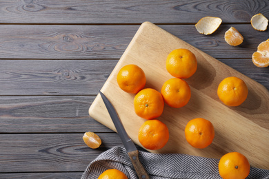 Photo of Fresh ripe tangerines and peel on wooden table, flat lay