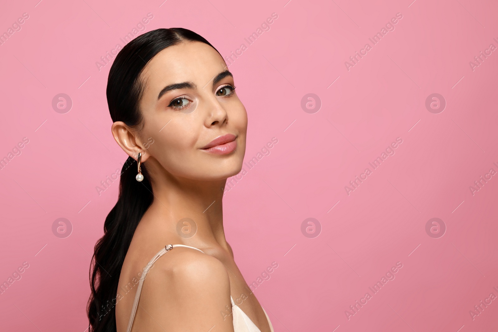 Photo of Young woman wearing elegant pearl earrings on pink background, space for text