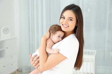 Photo of Happy woman holding her baby in light nursery