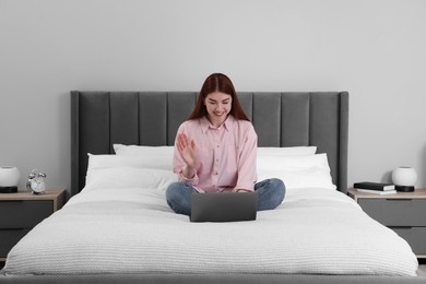 Happy woman having video chat via laptop on bed in bedroom