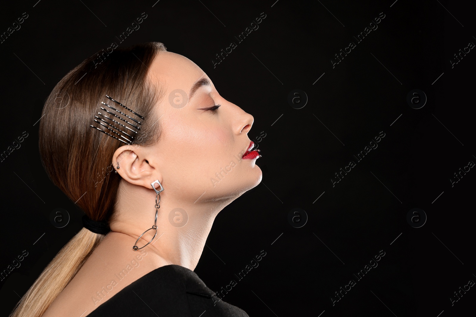 Photo of Young woman with lip and ear piercings on black background, space for text