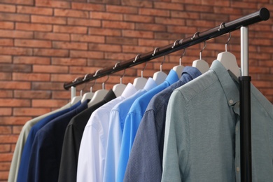 Wardrobe rack with stylish clothes near brick wall