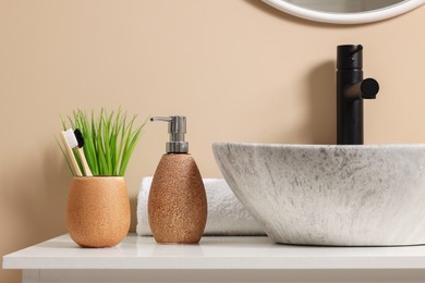 Different bath accessories and personal care products near sink on bathroom vanity