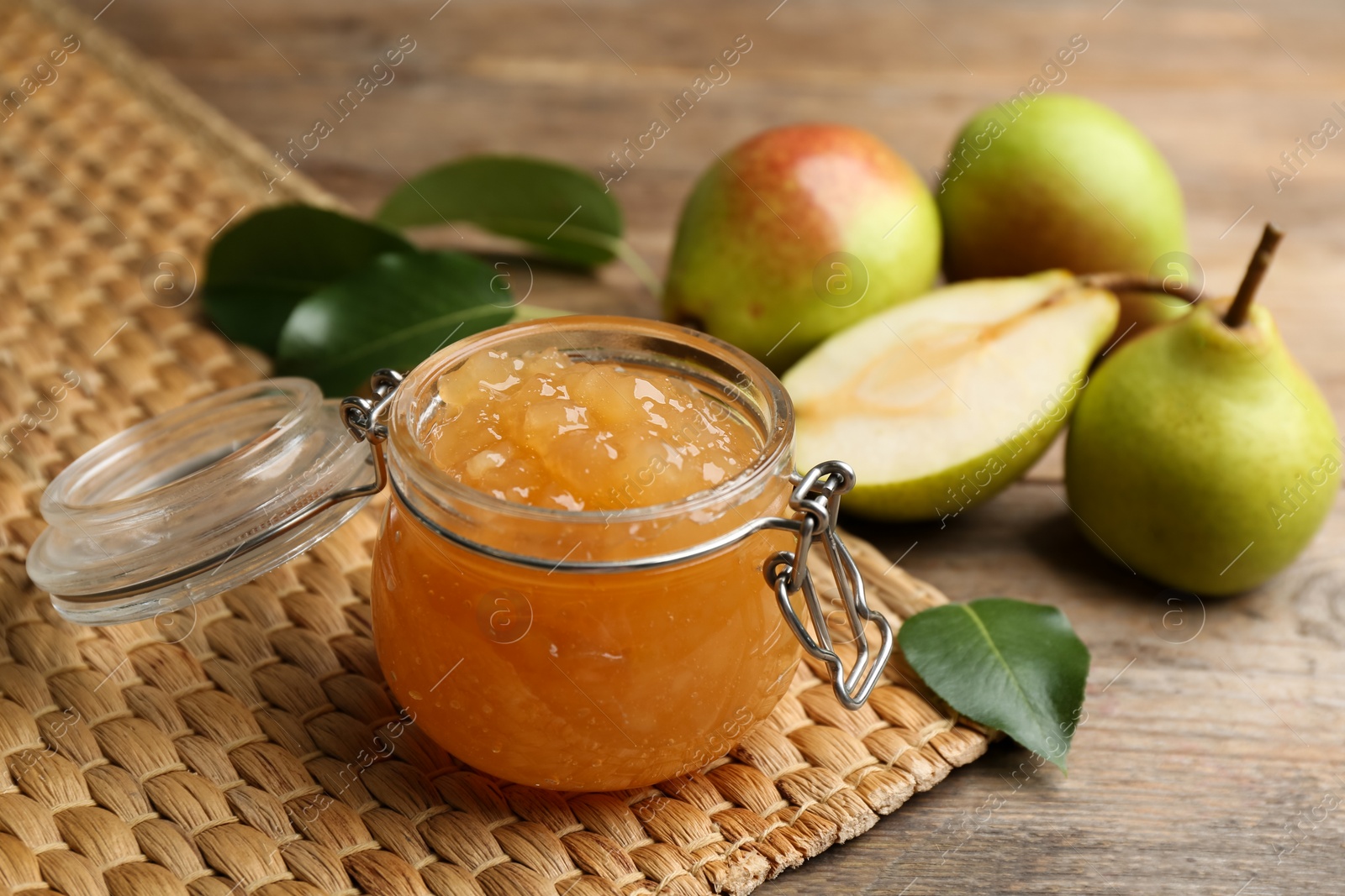 Photo of Delicious pear jam and fresh fruits on wooden table