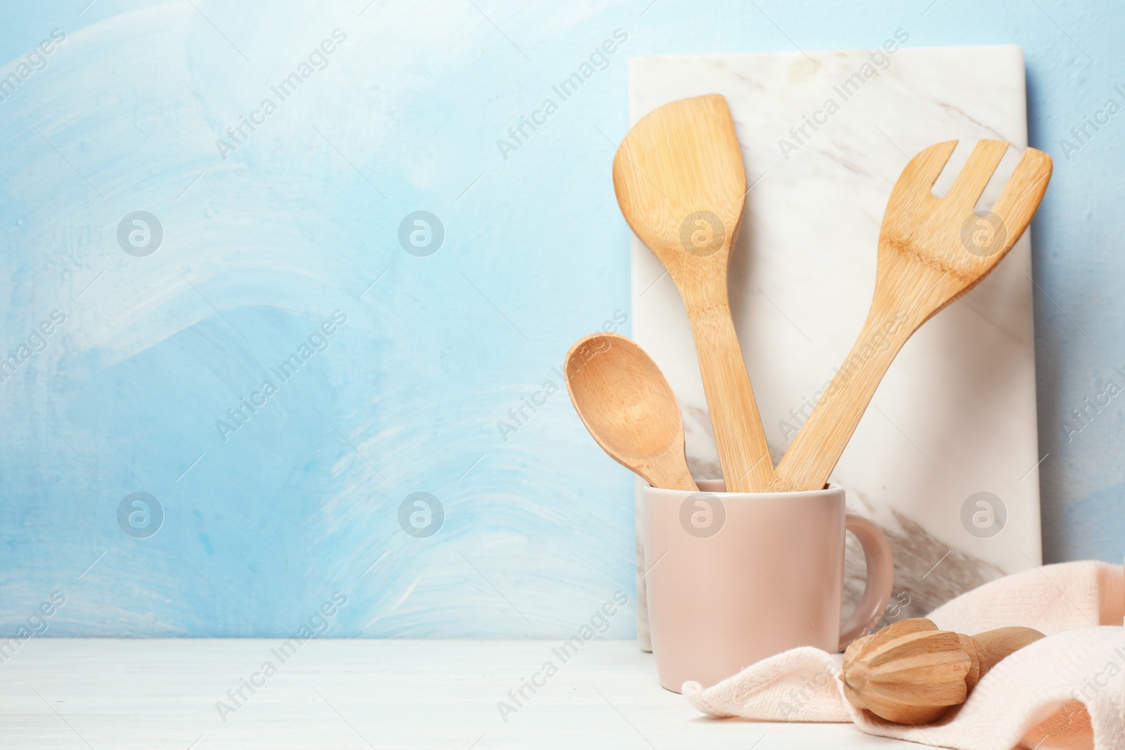 Photo of Wooden kitchen utensils, board and napkin on table. Space for text