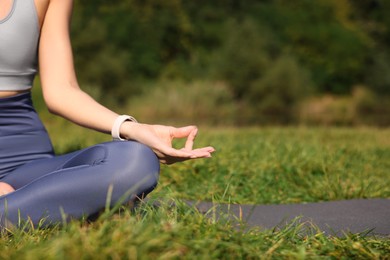 Photo of Woman practicing yoga on mat outdoors, closeup and space for text. Lotus pose