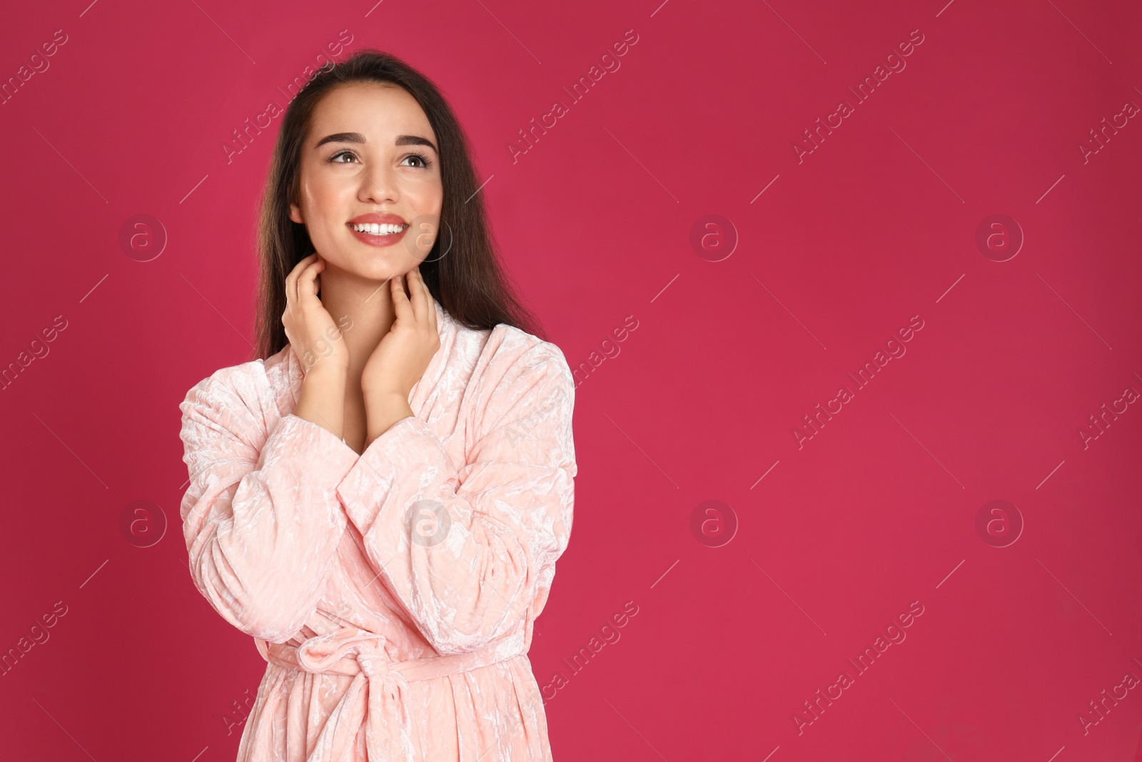 Photo of Beautiful young woman in bathrobe on crimson background. Space for text
