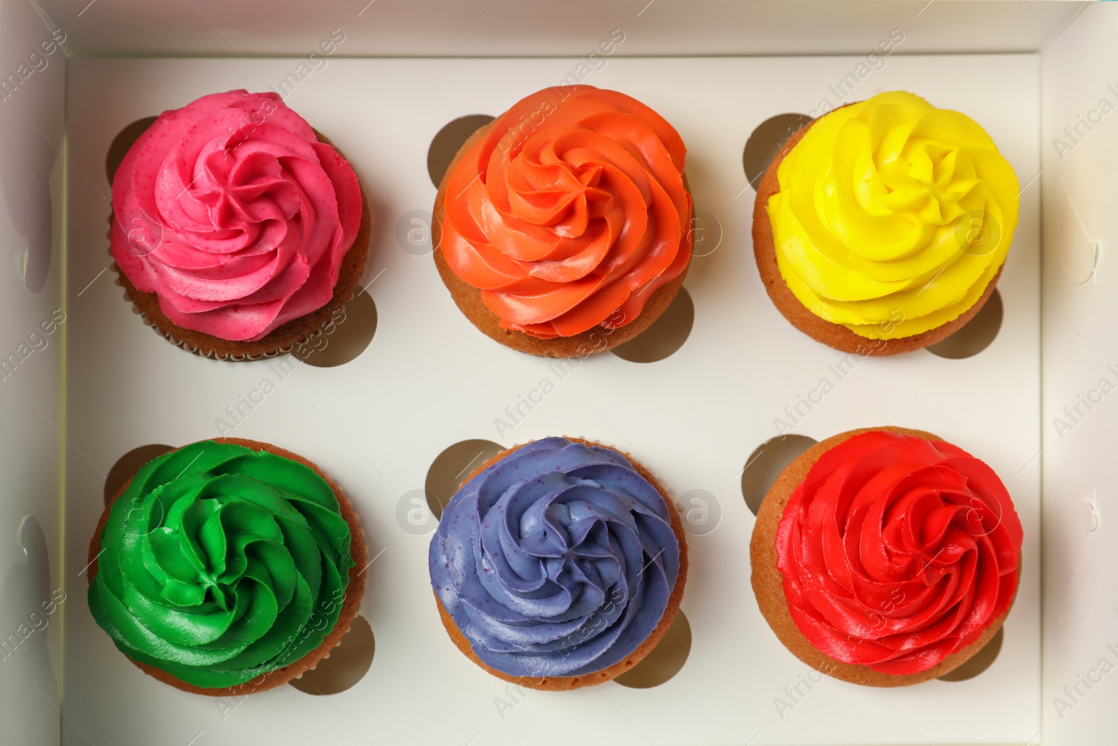 Photo of Many delicious colorful cupcakes in box, top view