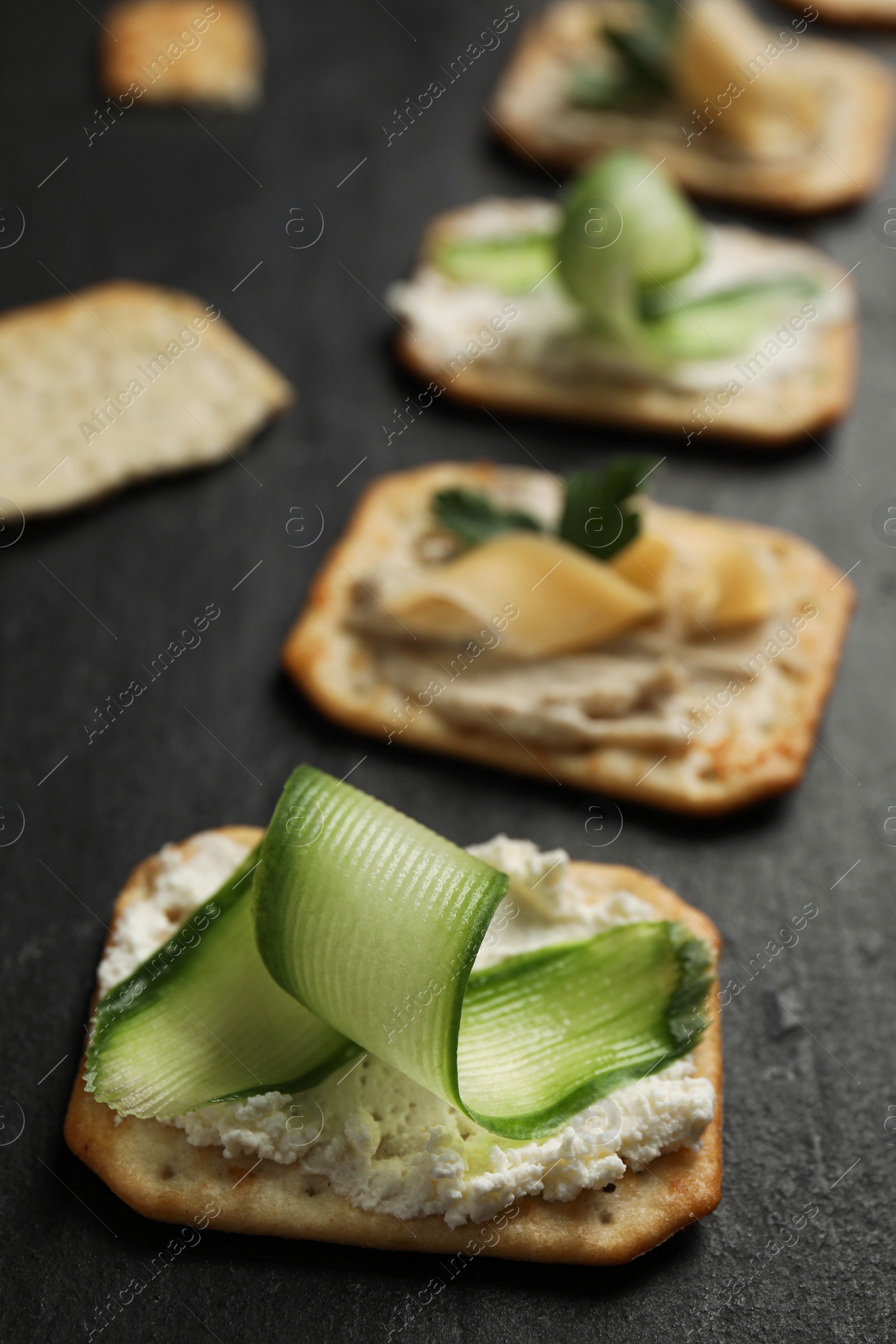 Photo of Delicious crackers with humus and cheese on black table, closeup