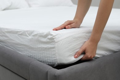 Woman putting new soft mattress on bed, closeup