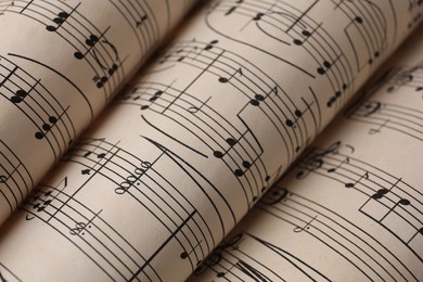 Photo of Rolled sheets with music notes as background, closeup