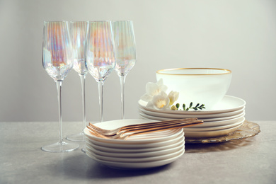 Photo of Set of glasses and dishes with flowers on light grey table