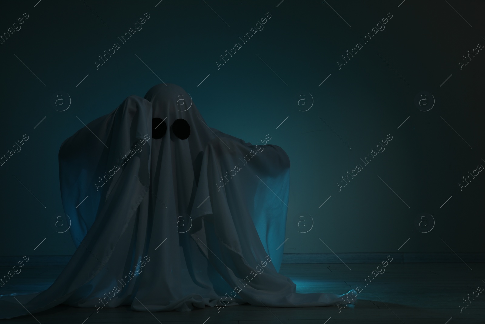 Photo of Creepy ghost. Woman covered with sheet on dark background, space for text