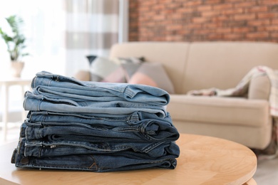 Photo of Stack of stylish jeans on table against blurred background