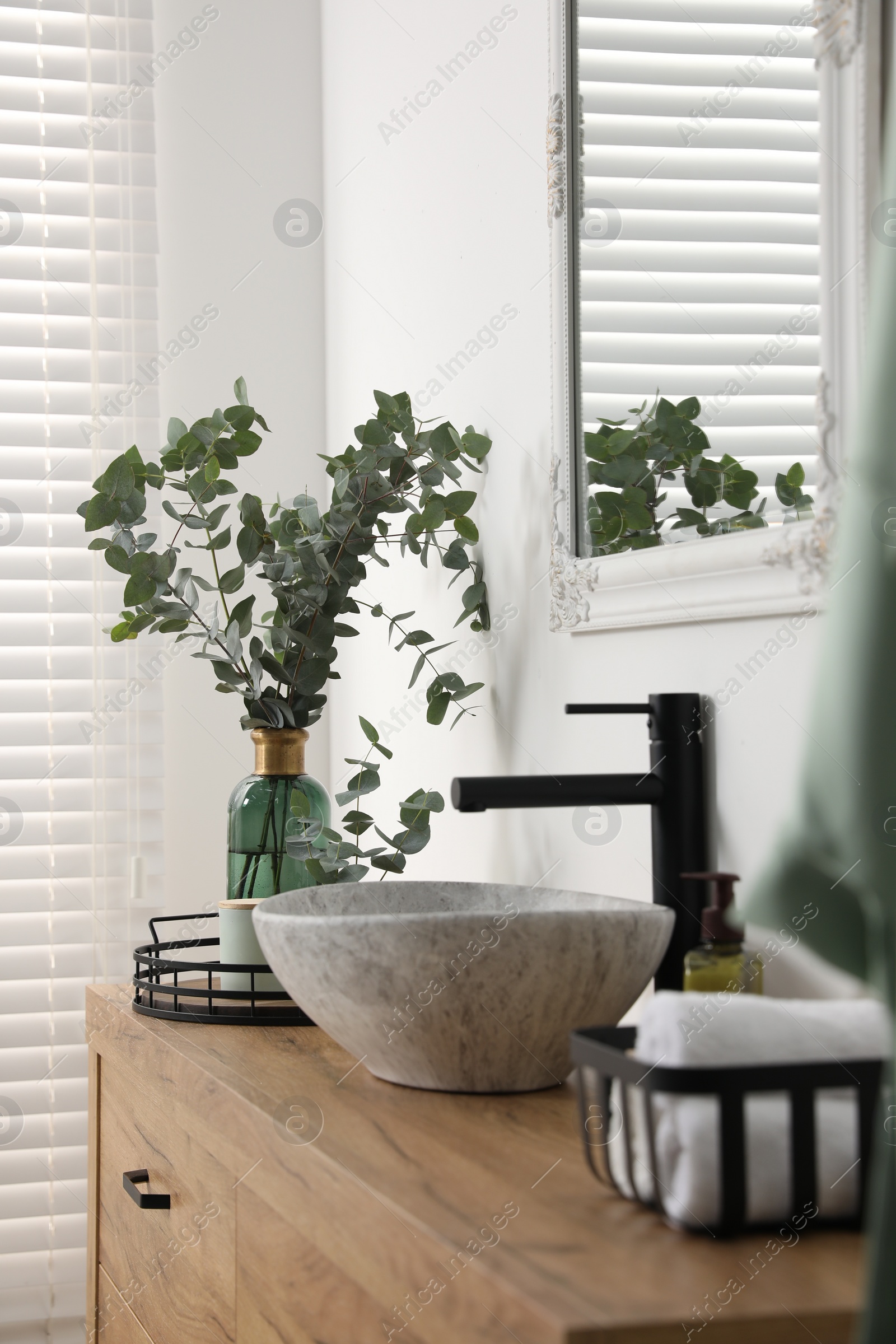 Photo of Modern bathroom interior with stylish mirror, eucalyptus branches, vessel sink and wooden vanity