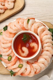 Tasty boiled shrimps with cocktail sauce, chili and parsley on light wooden table, flat lay