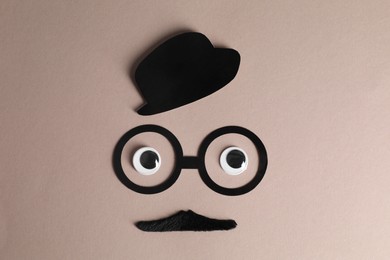 Man's face made of fake mustache, paper hat and glasses on grey background, top view