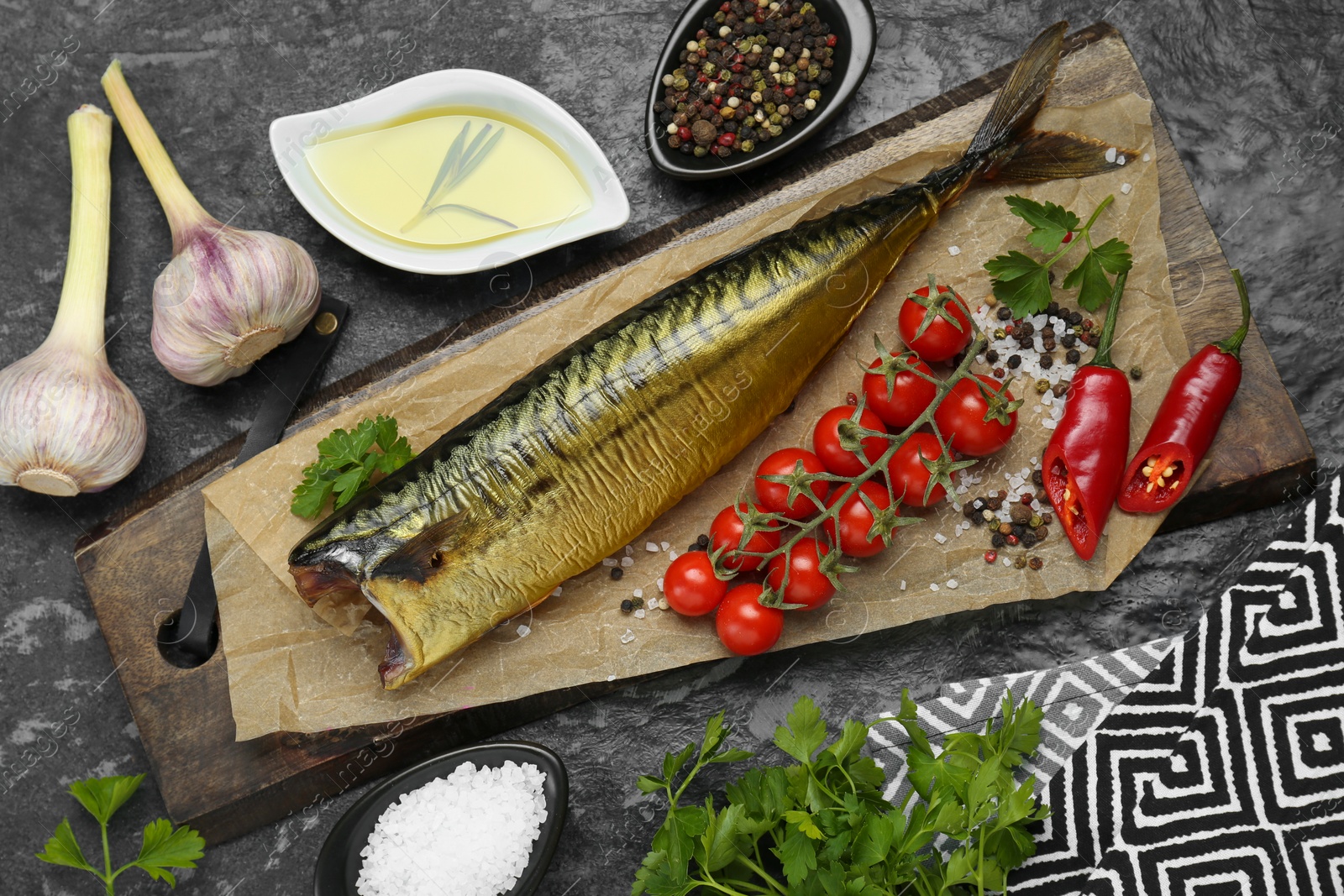 Photo of Delicious smoked mackerel and different products on black textured table, flat lay