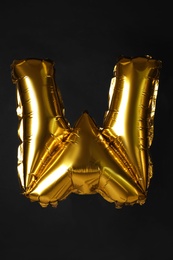 Photo of Golden letter W balloon on black background