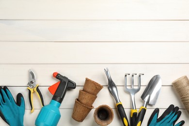 Flat lay composition with gardening tools on white wooden background, space for text