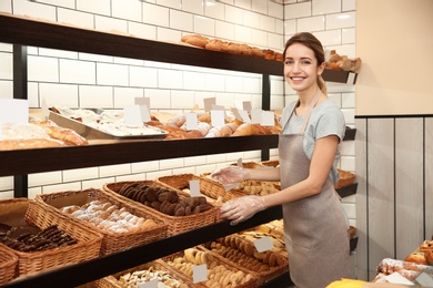 Photo of Beautiful woman near showcase with pastries in bakery shop