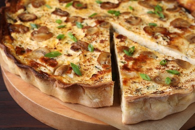 Photo of Delicious pie with mushrooms and cheese on wooden serving board, closeup