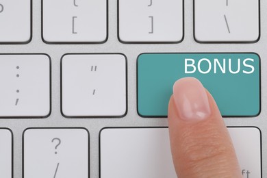 Woman pressing turquoise Bonus button on keyboard, closeup