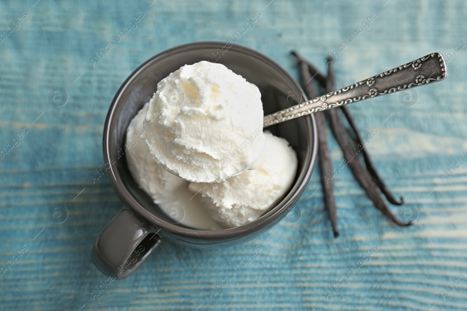 Photo of Cup with tasty vanilla ice cream on wooden background