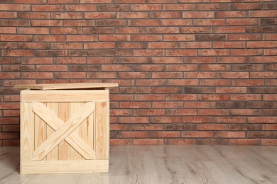 Photo of Wooden crate on floor at brick wall. Space for text