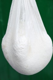 Photo of Delicious raw cottage cheese in cheesecloth on green background