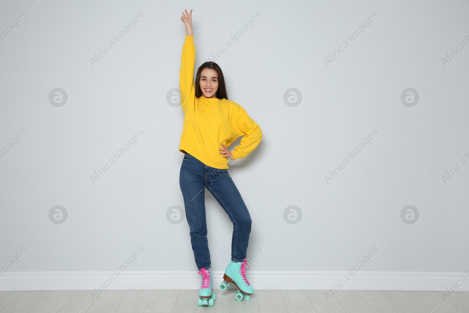 Photo of Full length portrait of young woman with roller skates near color wall