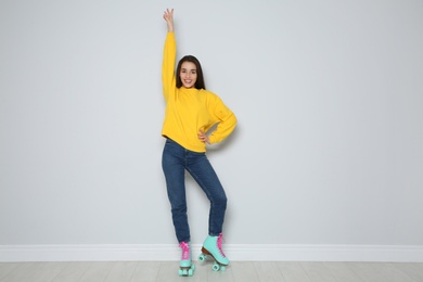 Photo of Full length portrait of young woman with roller skates near color wall