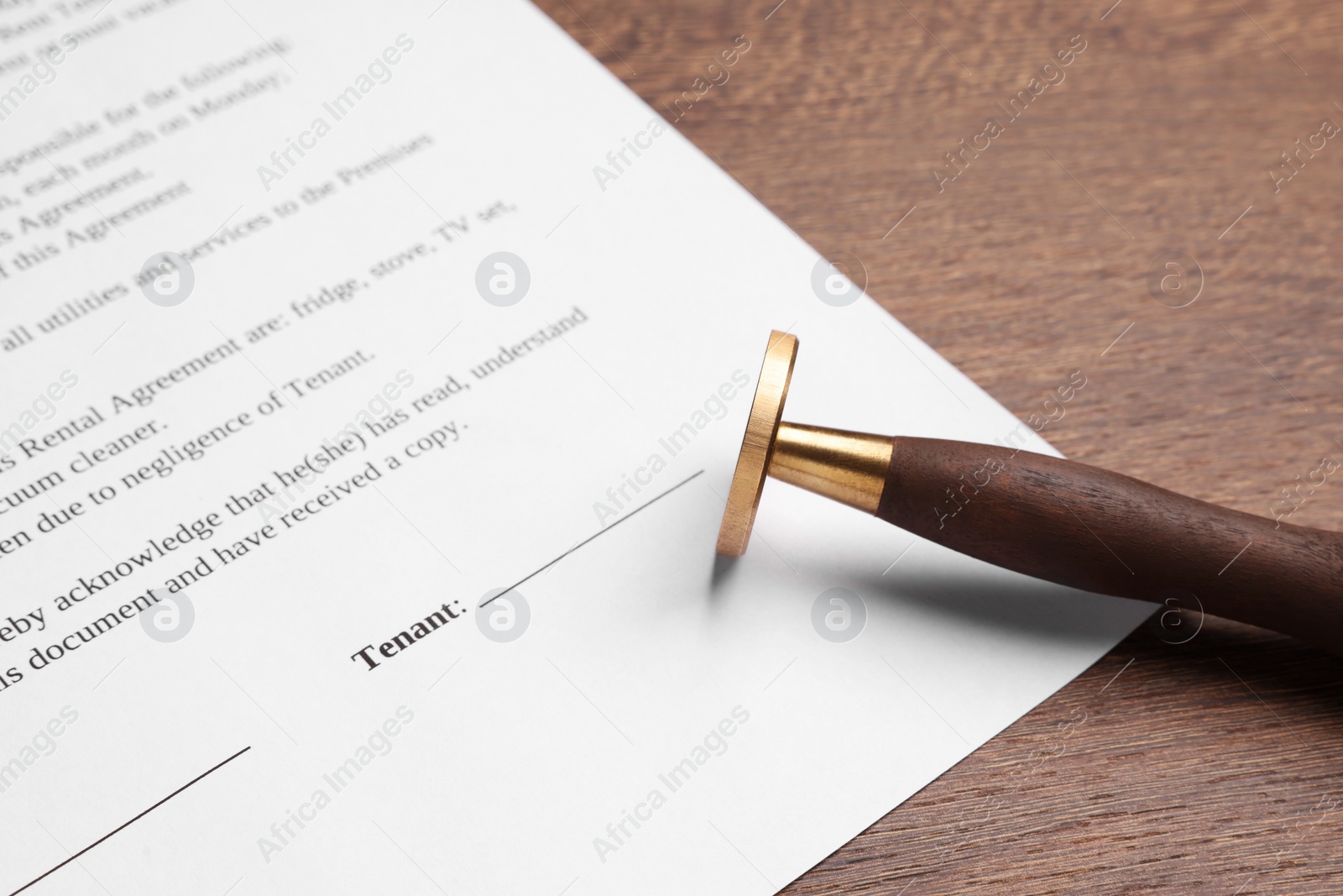 Photo of One stamp tool and document on wooden table, closeup