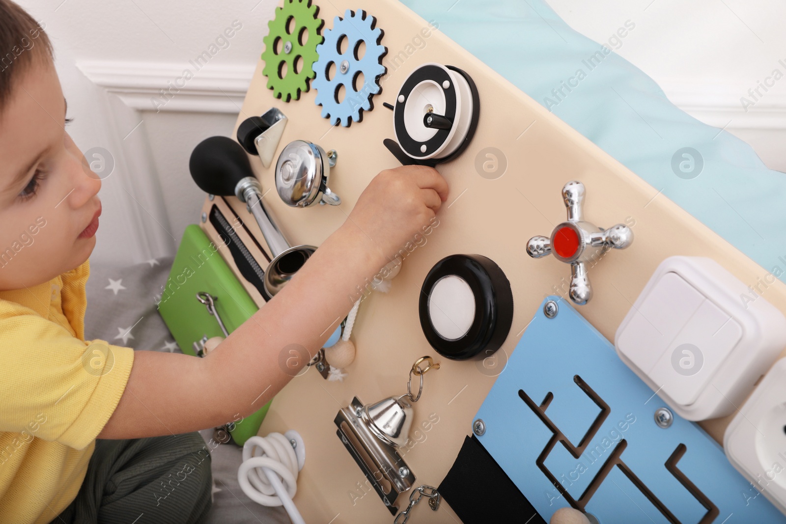 Photo of Little boy playing with busy board on bed