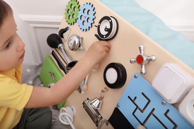 Photo of Little boy playing with busy board on bed