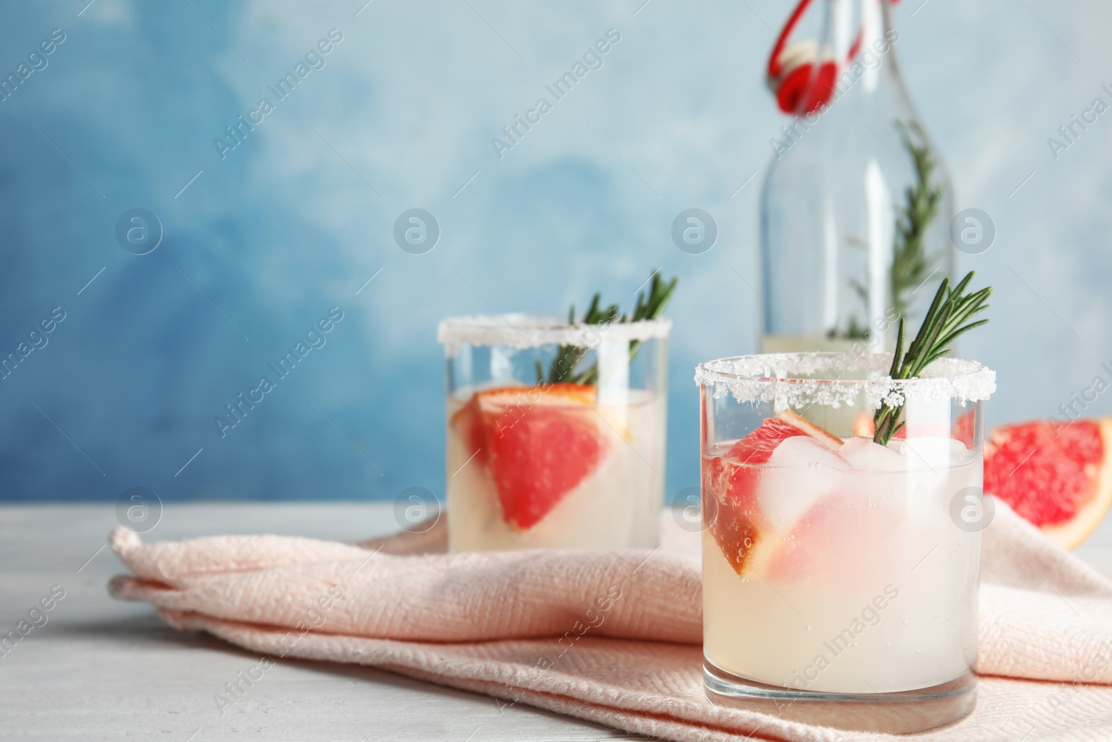 Photo of Glasses of grapefruit cocktails served on table against color background. Space for text