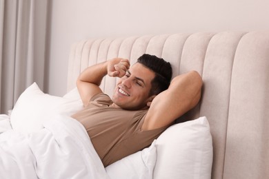 Happy man awakening in bed at home