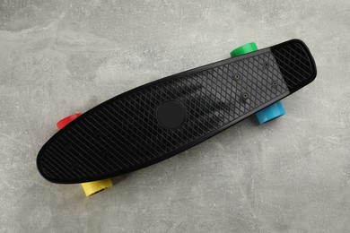 Black skateboard on grey stone background, top view. Sport equipment