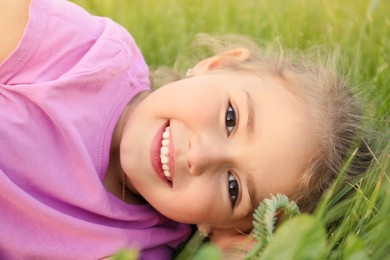 Photo of Cute little girl on green grass, closeup