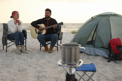 Photo of Lovely couple resting near camping tent on sandy beach