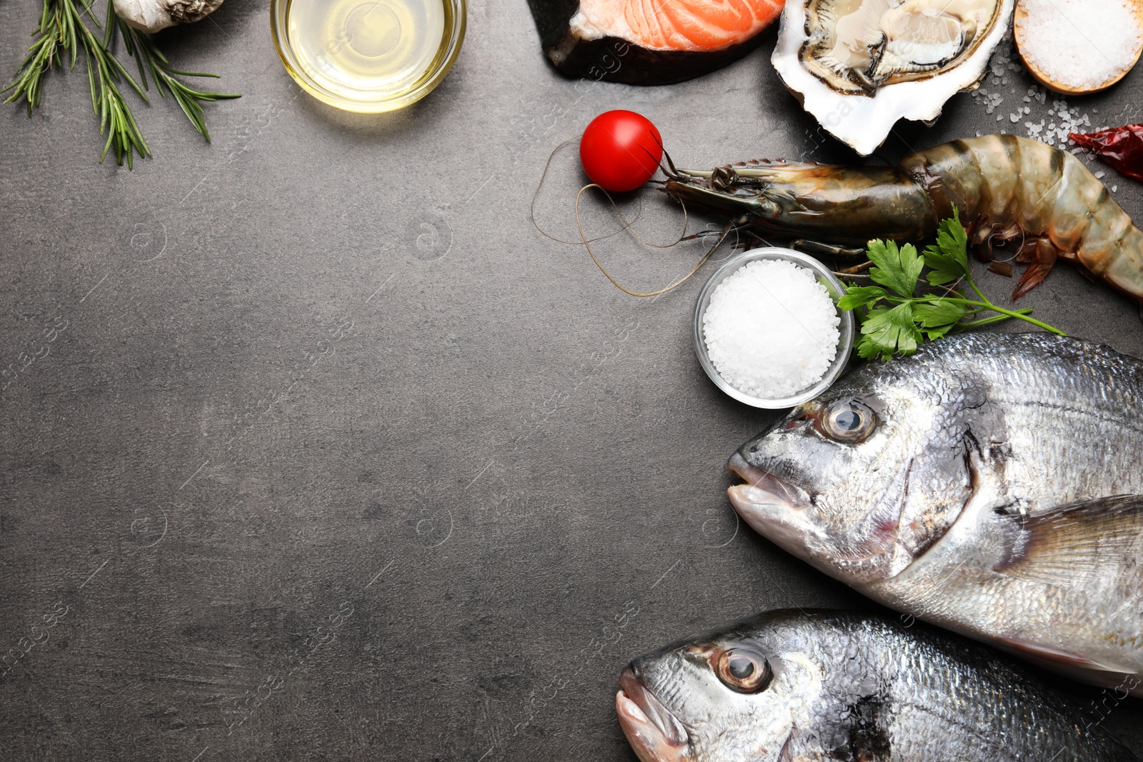 Photo of Frame of fresh raw dorado fish, shrimps and oyster on grey table, top view. Space for text